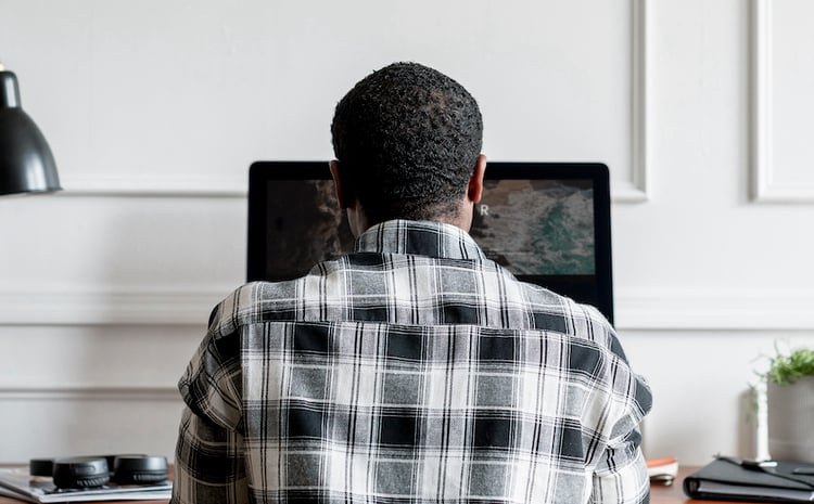 the back of a mans head as he looks at his computer screen